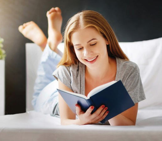 woman reading a book while laying in bed